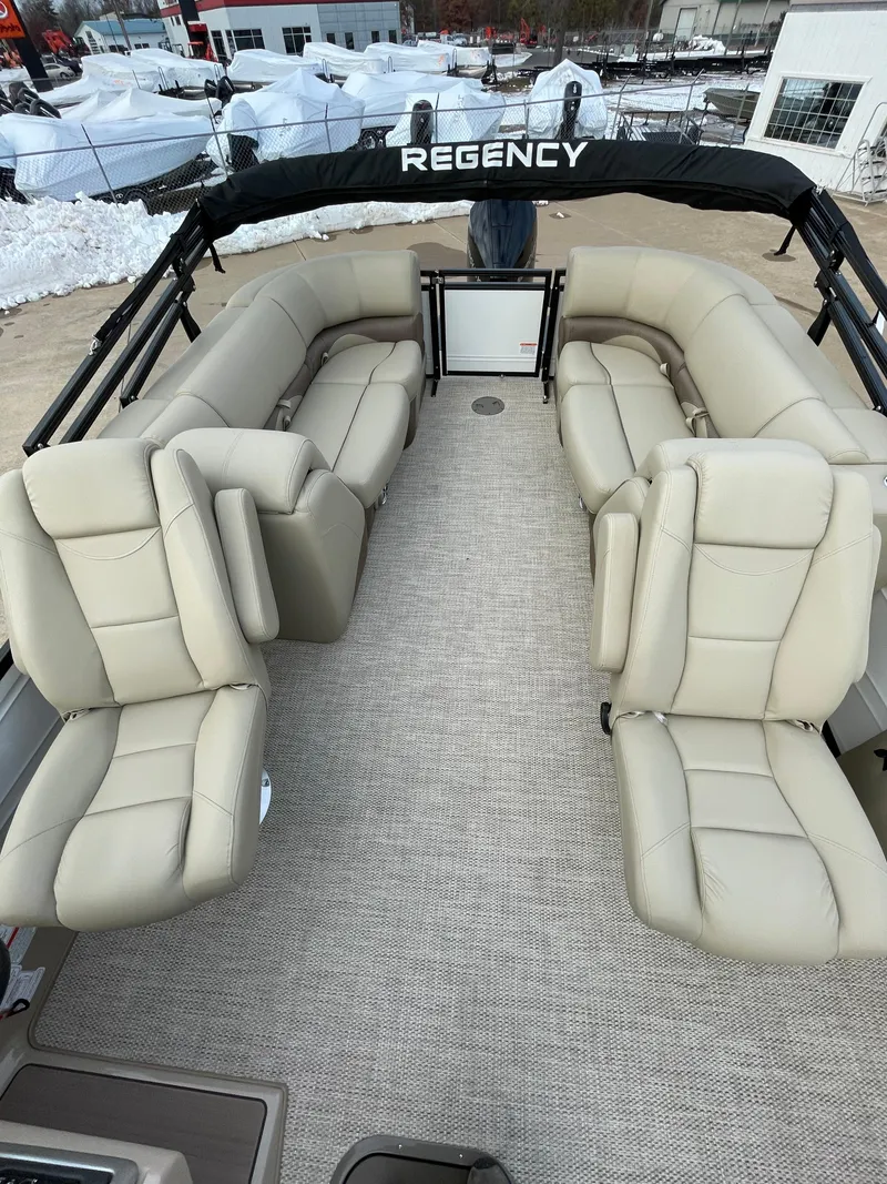 Slide: The Image of 2024 Regency 230 DL3 pontoon boat with spacious beige seating and carpeted deck. - 3