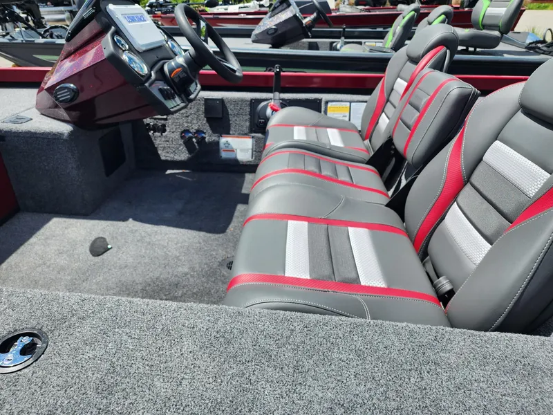 Slide: The Image of 2024 Ranger RT188C boat interior with gray and red seating, steering console, and carpeted flooring. - 2