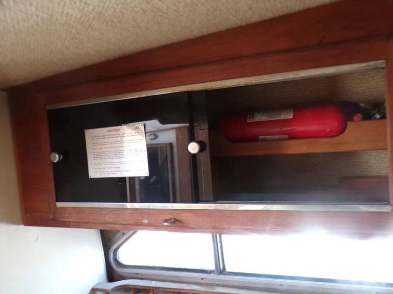 Slide: The Image of 1985 Boston Whaler Dual Console interior cabinet with fire extinguisher. - 16