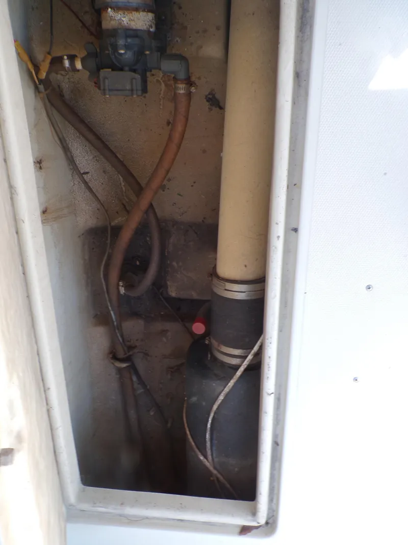 Slide: The Image of 1985 Boston Whaler Dual Console boat interior compartment with pipes and wiring. - 21