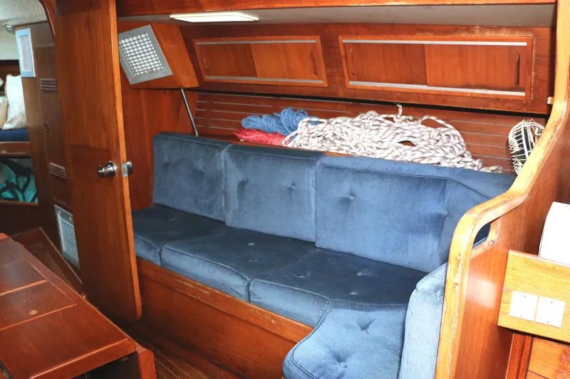 Slide: The Image of Interior of a 1985 Baltic 35 sailboat with blue cushioned seating and wooden cabinetry. - 21