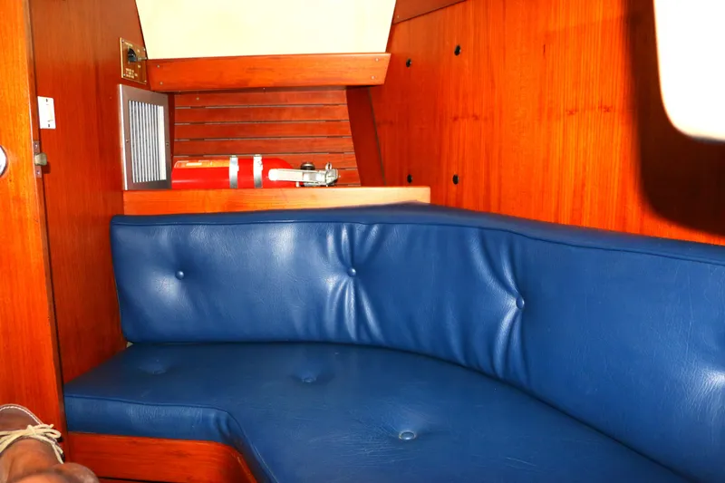 Slide: The Image of 1985 Baltic 35 yacht interior with blue leather seating and wooden paneling. - 23
