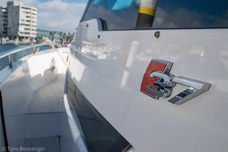 Slide: The Image of 2018 Axopar 37 Sun-Top boat with sleek design and emblem, docked in a marina. - 18