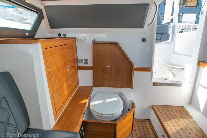 Slide: The Image of 2018 Axopar 37 Sun-Top boat interior with wooden cabinetry and compact toilet. - 25