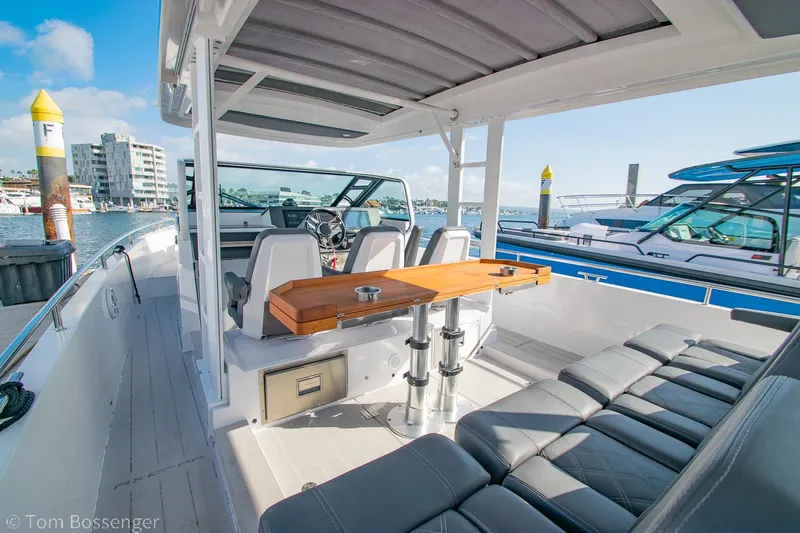 Slide: The Image of 2018 Axopar 37 Sun-Top boat interior with seating and table, docked at marina. - 5