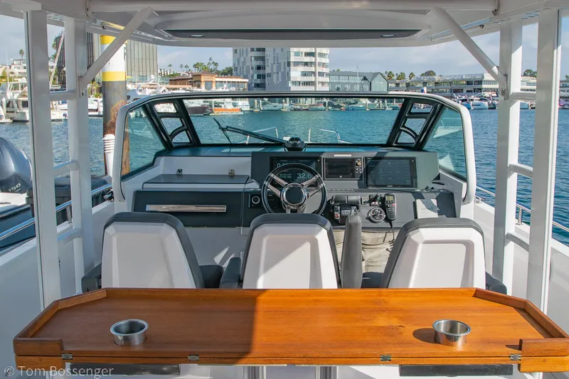Slide: The Image of 2018 Axopar 37 Sun-Top boat interior with helm, seating, and wooden table. - 6