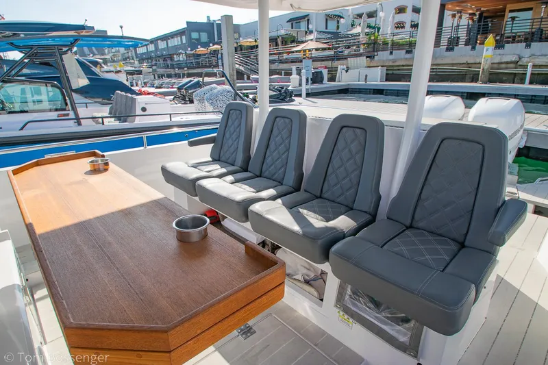 Slide: The Image of 2018 Axopar 37 Sun-Top boat interior with gray seating and wooden table at marina. - 7