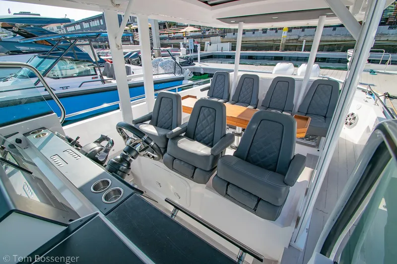 Slide: The Image of 2018 Axopar 37 Sun-Top boat interior with seating and helm, docked at marina. - 9