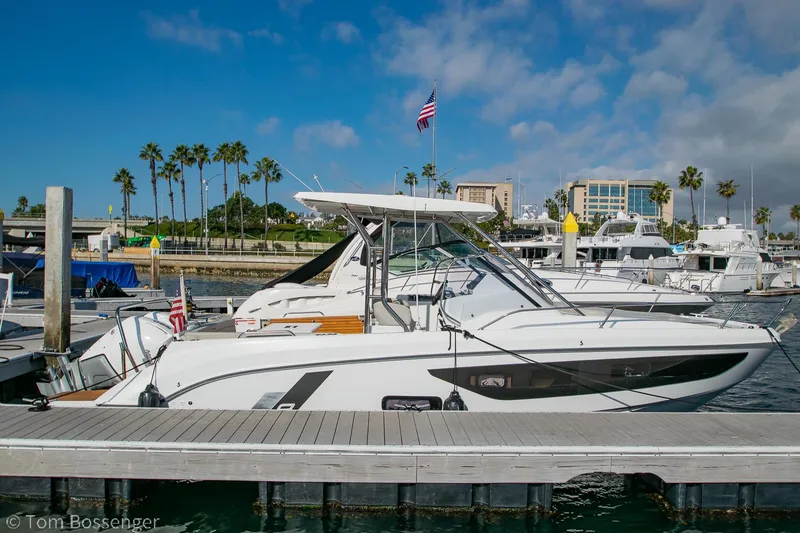 Slide: The Image of 2022 Beneteau Flyer 9 docked at marina with palm trees and buildings in background. - 0