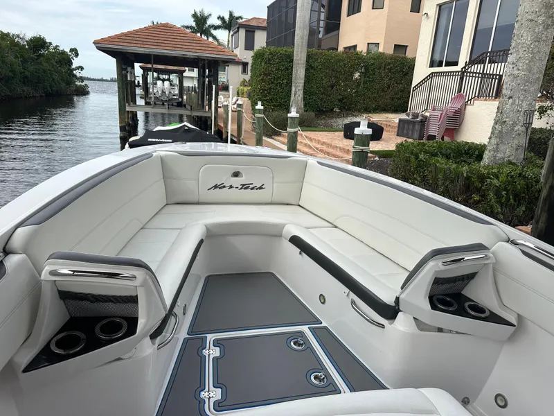 Slide: The Image of 2021 Nor-Tech 390 Sport boat with white seating and cup holders docked by waterfront homes. - 32
