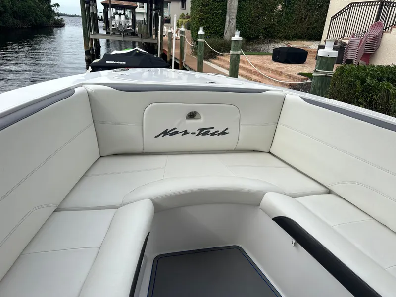 Slide: The Image of 2021 Nor-Tech 390 Sport boat with white cushioned seating at the bow, docked by the water. - 34
