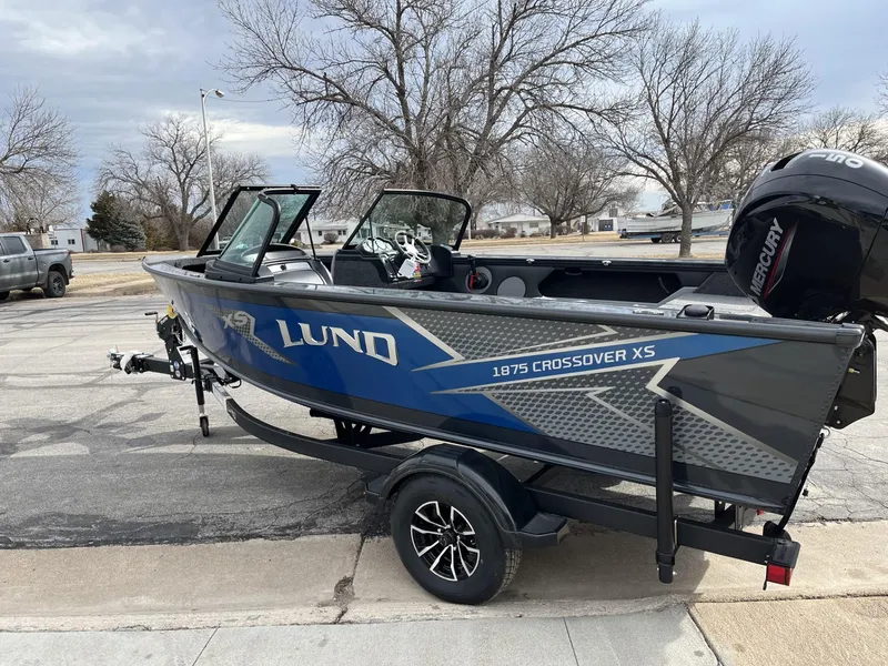 Slide: The Image of 2025 Lund 1875 Crossover XS boat on a trailer in a residential area. - 7