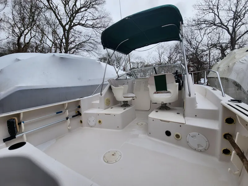 Slide: The Image of 1997 Pro-Line 201 Walkaround boat with canopy, docked outdoors, surrounded by trees. - 17