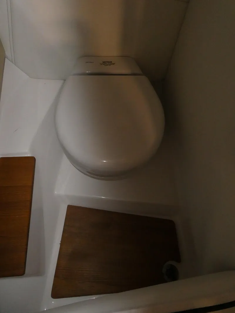 Slide: The Image of 2024 Regal LX9 boat bathroom with modern toilet and wooden floor mats. - 19