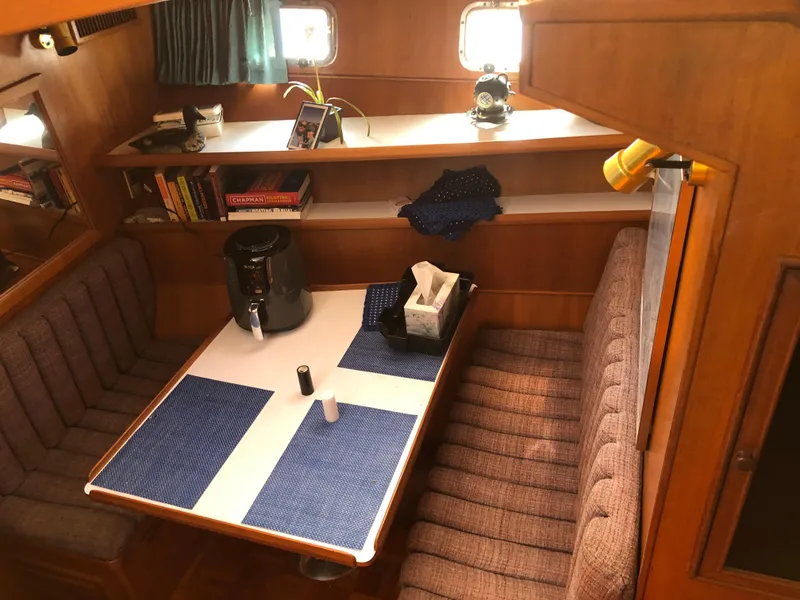 Slide: The Image of Cozy dining area in a 1985 CHB Motor Yacht with bookshelves and seating. - 15