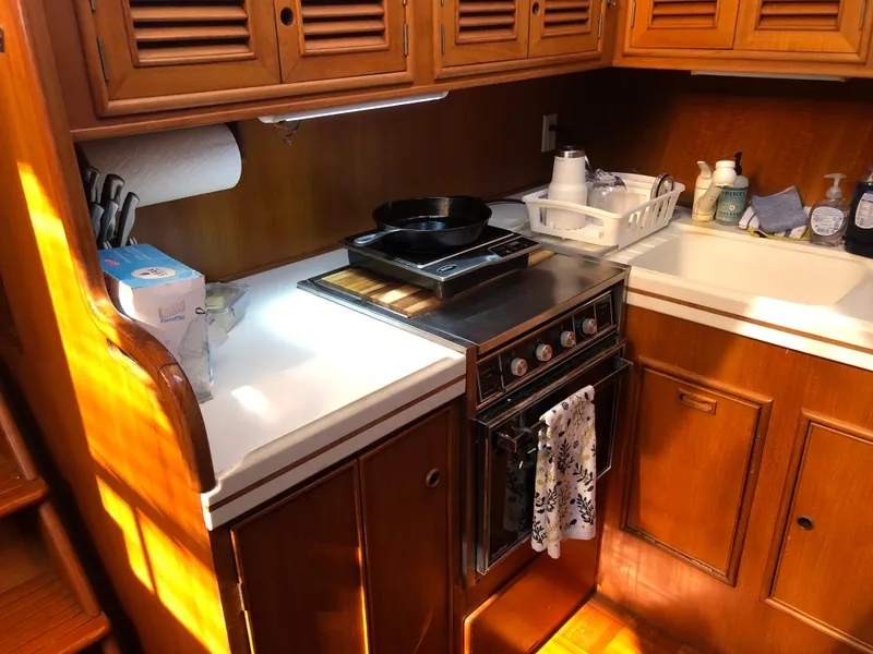 Slide: The Image of 1985 CHB Motor Yacht kitchen with stove, sink, and wooden cabinets. - 16