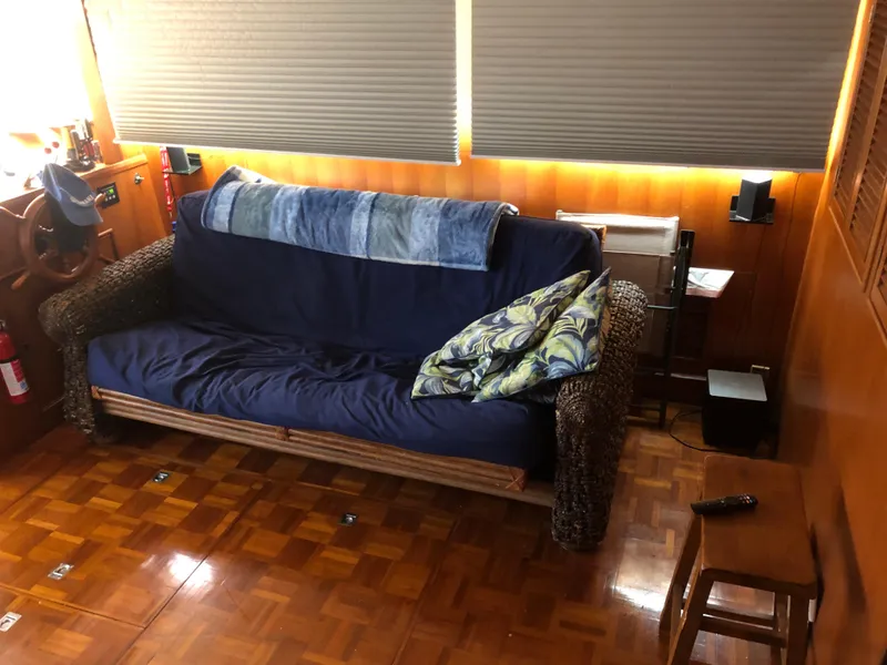 Slide: The Image of Interior of 1985 CHB Motor Yacht with wicker sofa, blue cushions, and wooden flooring. - 17