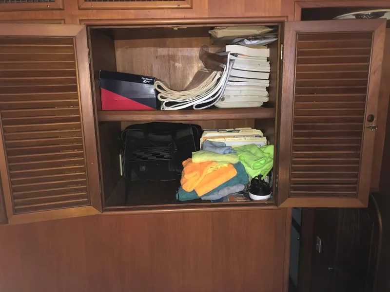 Slide: The Image of Open wooden cabinet on 1985 CHB Motor Yacht with towels, files, and a Reebok shoebox. - 35