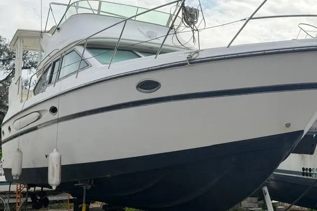 Slide: The Image of 2000 Maxum 4100 SCA yacht on dry dock, white hull with black bottom paint. - 103