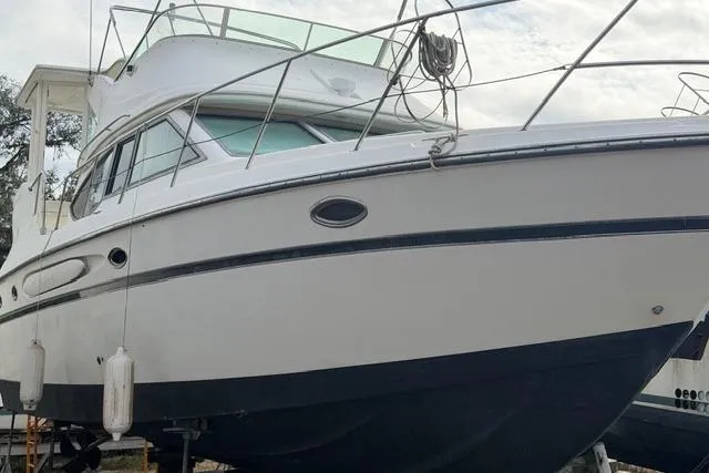 Slide: The Image of 2000 Maxum 4100 SCA yacht with white hull and upper deck, docked on land. - 104