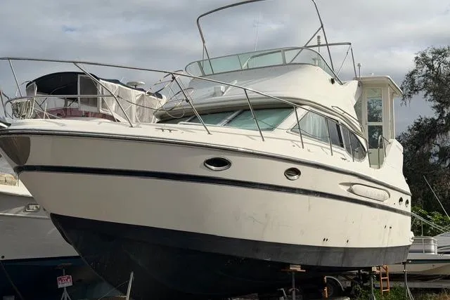 Slide: The Image of 2000 Maxum 4100 SCA yacht on dry dock, white hull, overcast sky. - 105