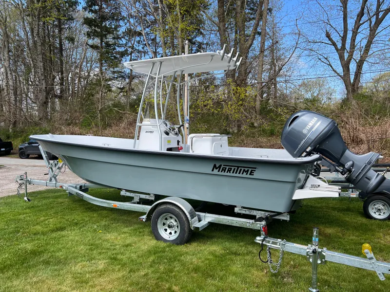 Slide: The Image of 2024 Maritime 2090 Skiff boat on trailer with outboard motor in grassy area. - 2