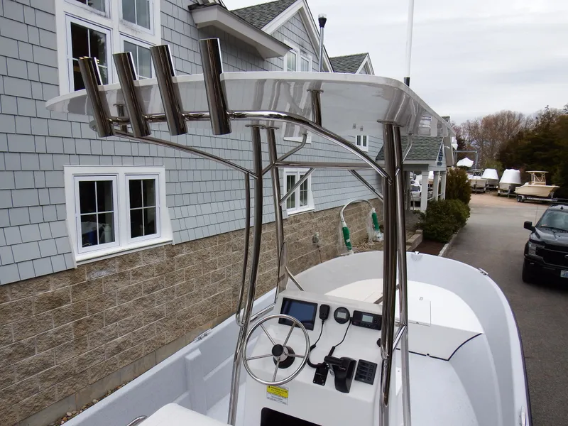 Slide: The Image of 2024 Maritime 2090 Skiff boat with T-top and console, parked near a house. - 22