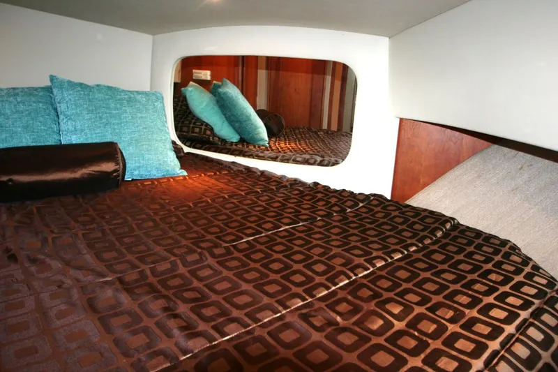 Slide: The Image of 2000 Silverton 392 Motor Yacht bedroom with brown geometric bedding and blue accent pillows. - 11