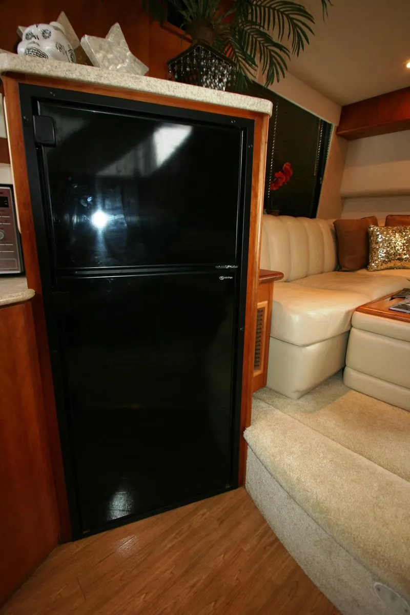 Slide: The Image of 2000 Silverton 392 Motor Yacht interior with black refrigerator and beige seating area. - 28