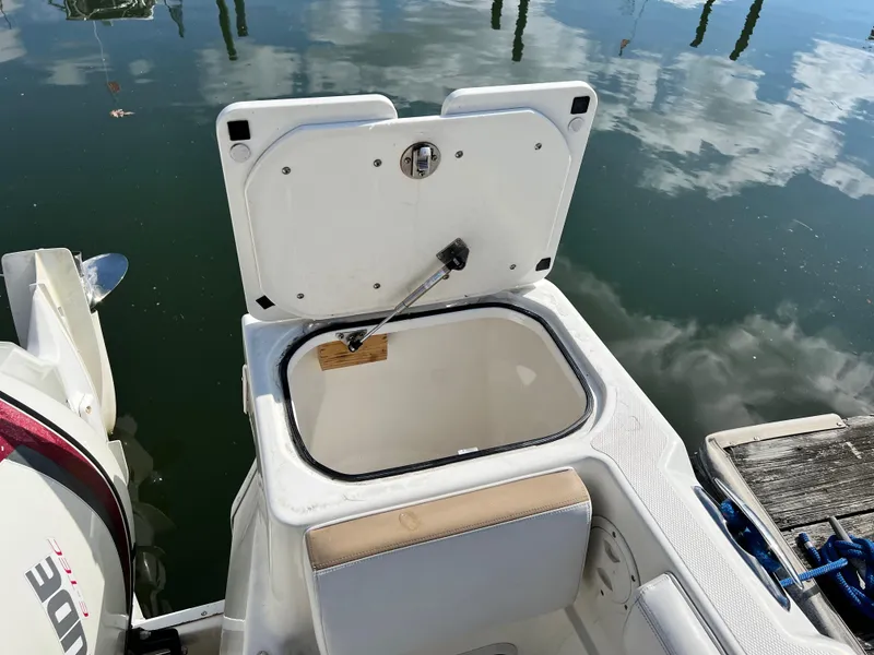 Slide: The Image of Open storage compartment on 2014 Striper 220 Center Console boat by the water. - 10