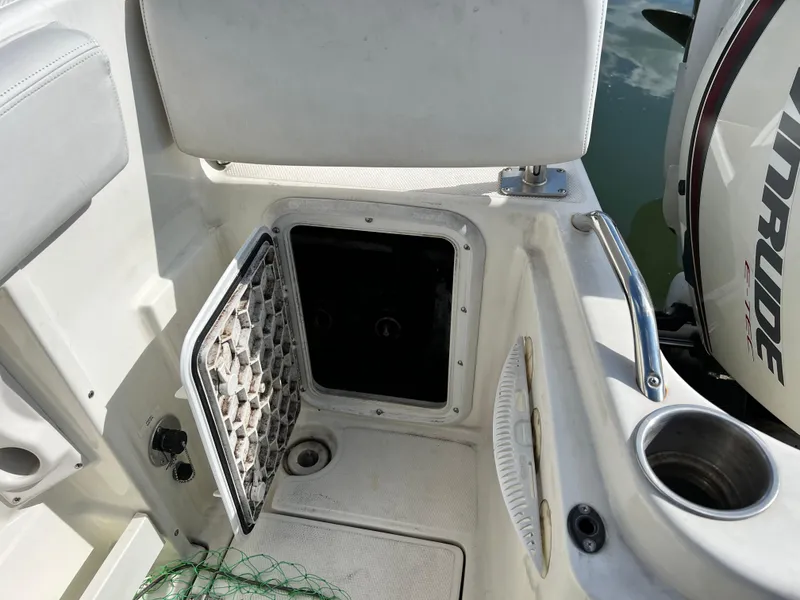 Slide: The Image of 2014 Striper 220 Center Console boat interior with open storage compartment and Evinrude engine. - 12