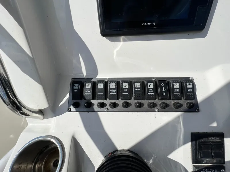 Slide: The Image of Control panel of a 2014 Striper 220 Center Console boat with various switches. - 24
