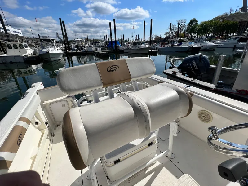 Slide: The Image of 2014 Striper 220 Center Console boat interior at marina, featuring seating and steering wheel. - 35