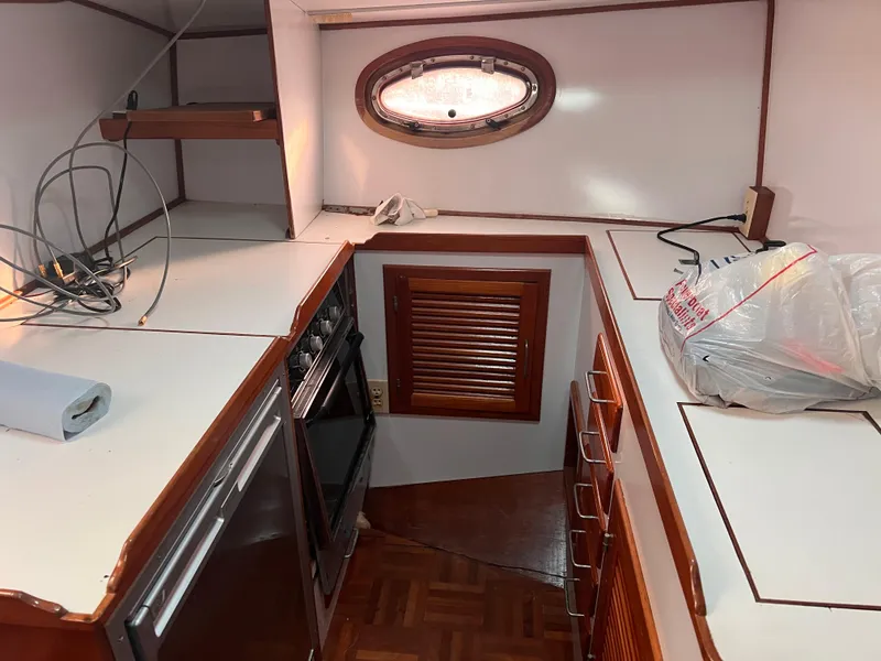Slide: The Image of 1988 Canyon Bay 40 boat kitchen interior with stove, cabinets, and porthole window. - 16