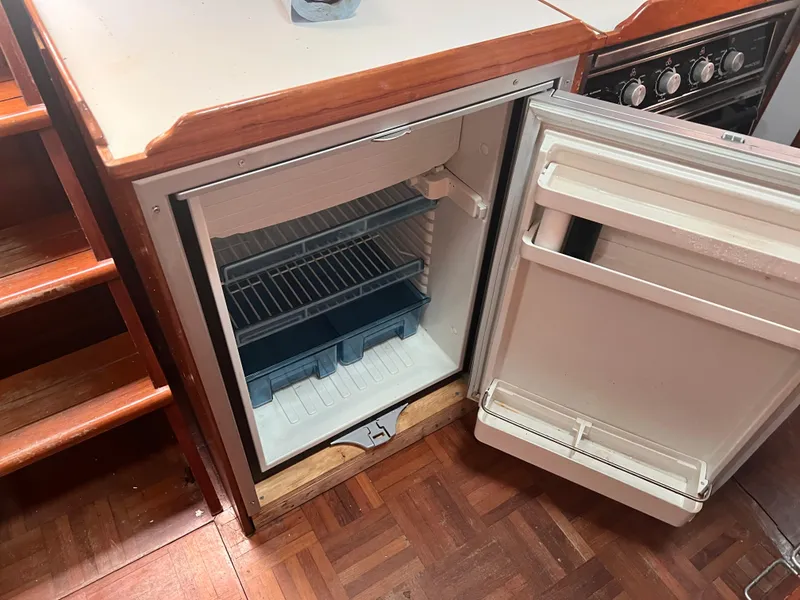 Slide: The Image of Open refrigerator in 1988 Canyon Bay 40 boat kitchen, showing empty shelves and wooden flooring. - 20