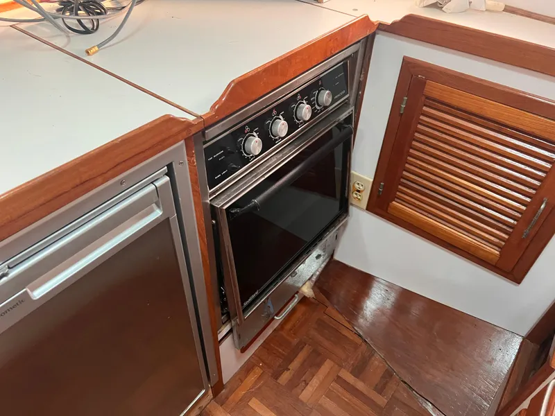 Slide: The Image of 1988 Canyon Bay 40 yacht kitchen with stove, wooden cabinetry, and parquet flooring. - 21
