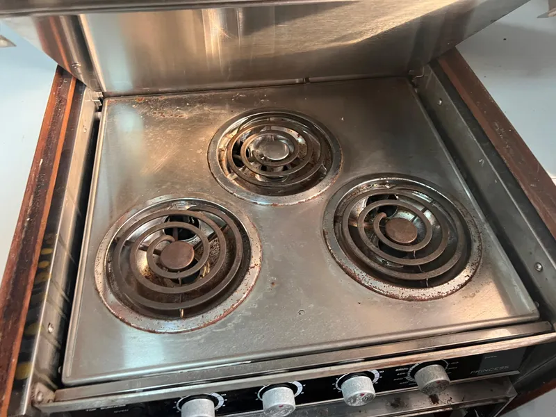 Slide: The Image of Old electric stove with three coil burners, showing signs of wear and rust. - 23