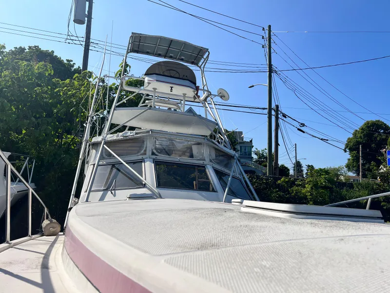 Slide: The Image of 1988 Canyon Bay 40 boat docked under clear blue sky, surrounded by greenery. - 3