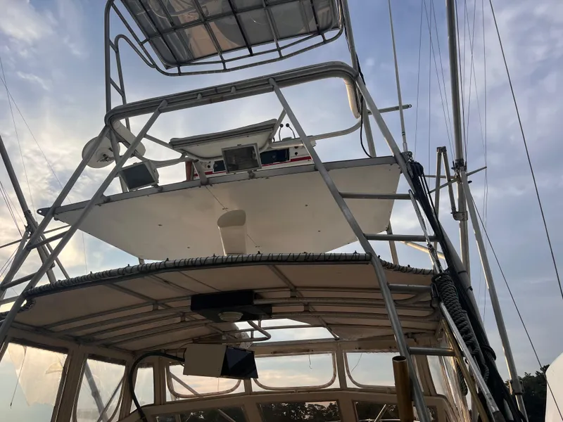 Slide: The Image of 1988 Canyon Bay 40 boat with upper deck and ladder under a cloudy sky. - 42