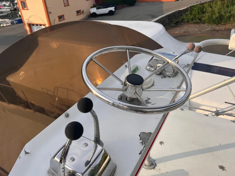 Slide: The Image of Steering wheel and controls of a 1988 Canyon Bay 40 boat, docked outdoors. - 48