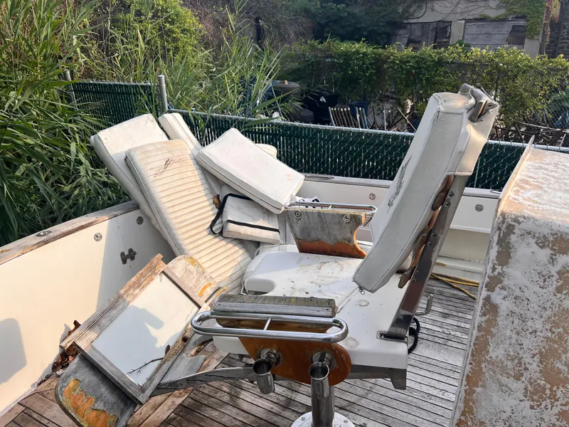 Slide: The Image of Abandoned 1988 Canyon Bay 40 boat with worn seats and overgrown surroundings. - 6