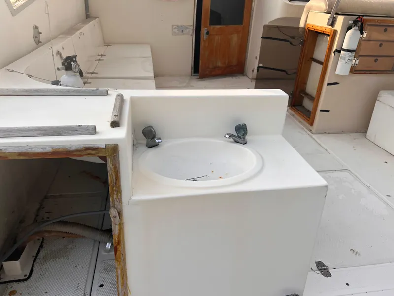 Slide: The Image of 1988 Canyon Bay 40 boat interior with sink, seating, and fire extinguisher. - 9