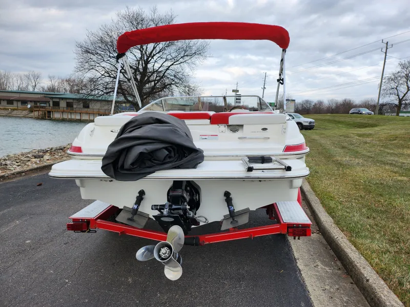 Slide: The Image of 2008 Glastron GT 205 boat with red canopy, parked near a lake. - 2