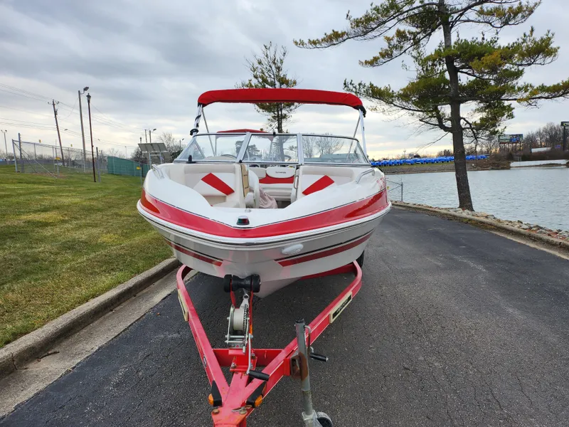 Slide: The Image of 2008 Glastron GT 205 boat with red accents on a trailer by a lake. - 6
