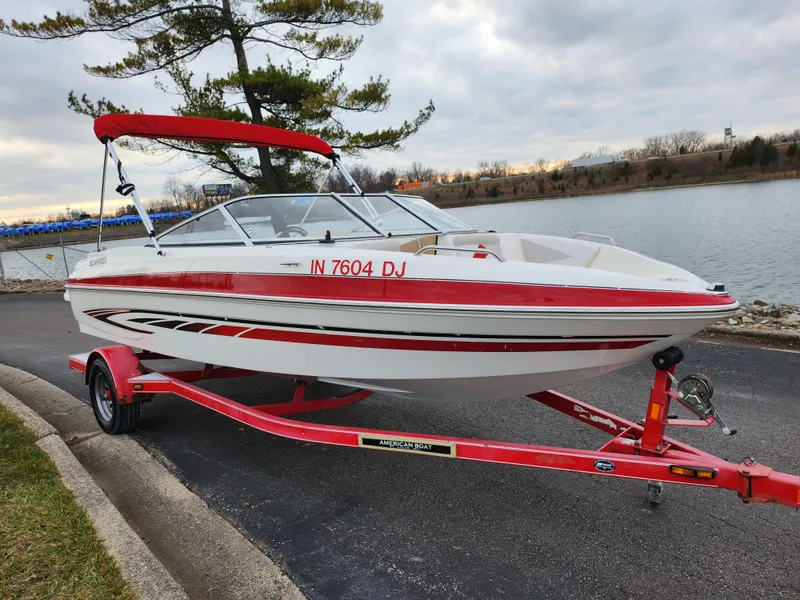 Slide: The Image of 2008 Glastron GT 205 boat with red accents on a matching trailer by a lake. - 8