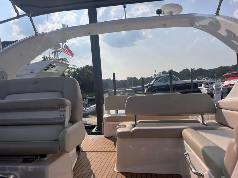 Slide: The Image of 2011 Regal 35 Express Cruiser interior with seating, docked at marina under sunny sky. - 10