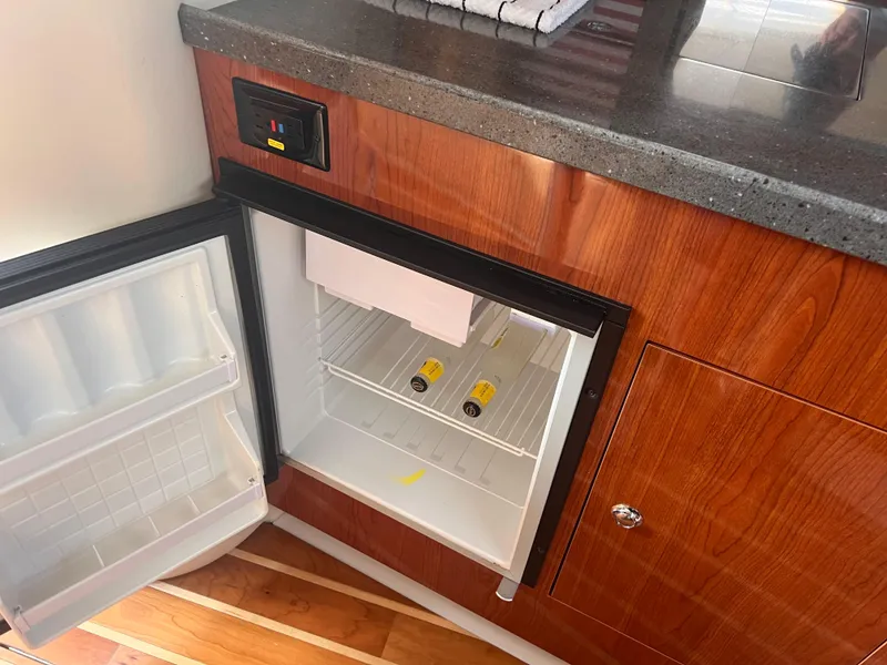 Slide: The Image of Open mini fridge in 2011 Regal 35 Express Cruiser, with wooden cabinetry and granite countertop. - 34