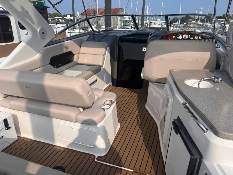 Slide: The Image of 2011 Regal 35 Express Cruiser interior with beige seating, wood flooring, and compact kitchenette. - 6
