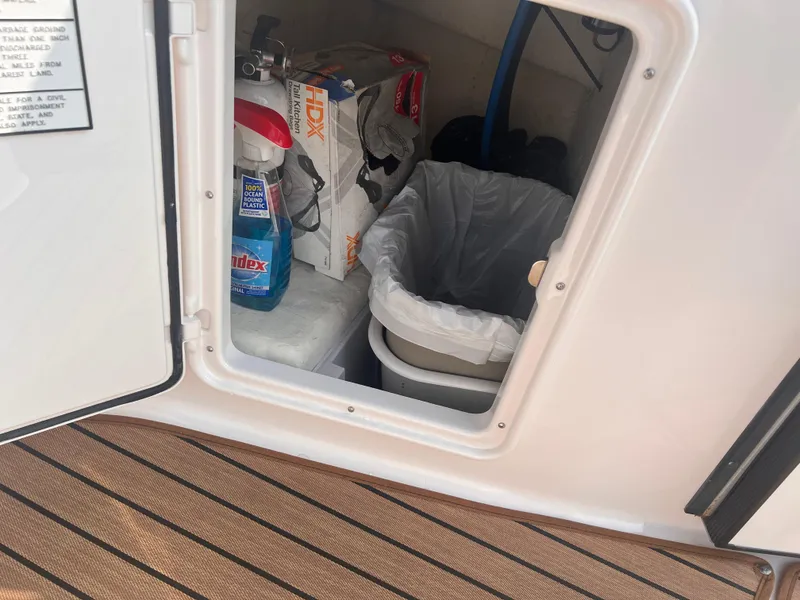 Slide: The Image of Storage compartment on a 2011 Regal 35 Express Cruiser with cleaning supplies and trash bin. - 9
