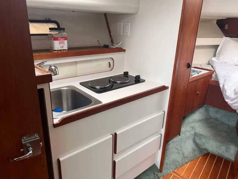 Slide: The Image of 1996 Pursuit 3100 Open boat interior with compact kitchen and cozy sleeping area. - 11